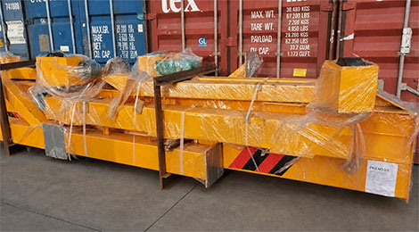 Portable gantry strapped to a steel pallet in front of shipping containers