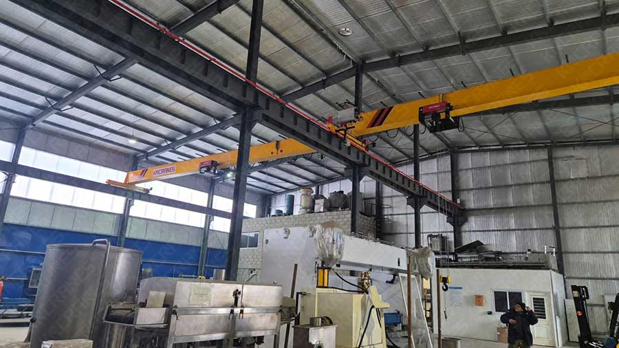 Overhead crane spanning the production hall above stainless steel process equipment