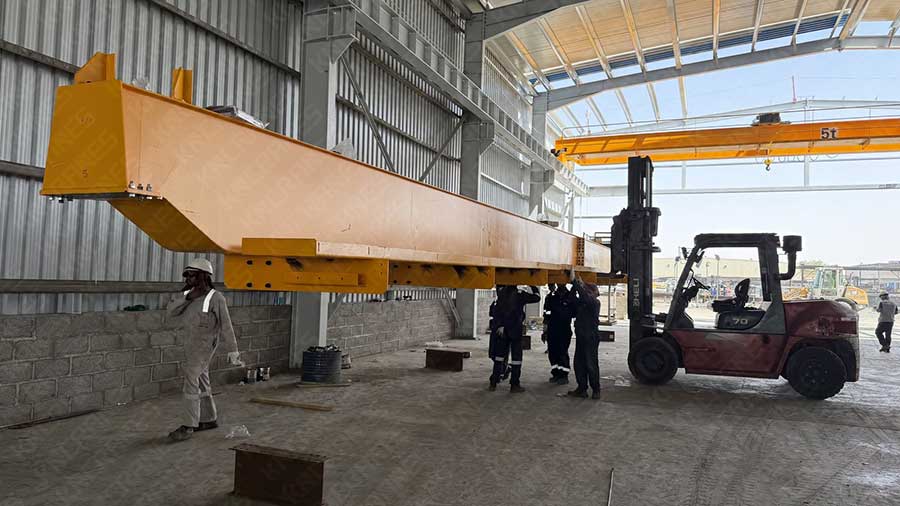 Main girder of a 5 ton double girder overhead crane being positioned on site, with an installed crane in the background