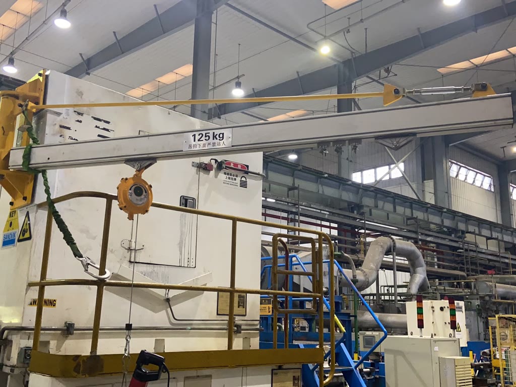 Wall-mounted aluminum jib crane 125 kg beside a machine